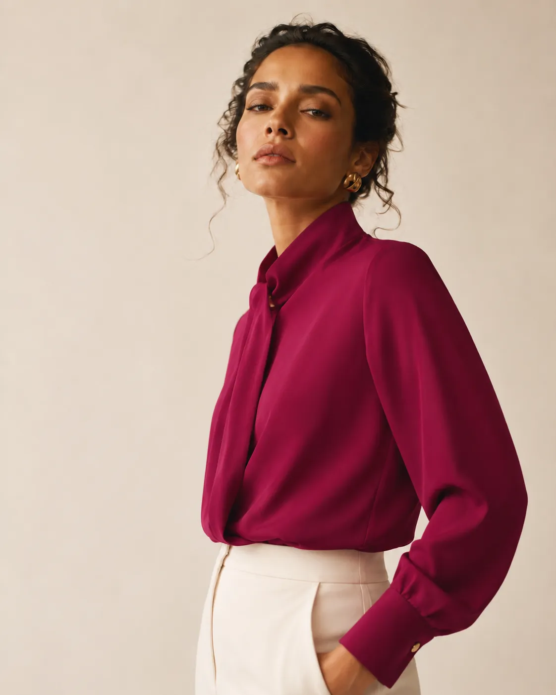Modelo veste blusa magenta estruturada de gola alta, sobre calça creme. Look desenvolvido no Coleção.Moda